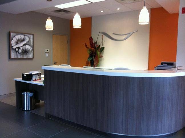 The reception desk at Moncton North Dental Center, with its orange feature wall and pendant lights