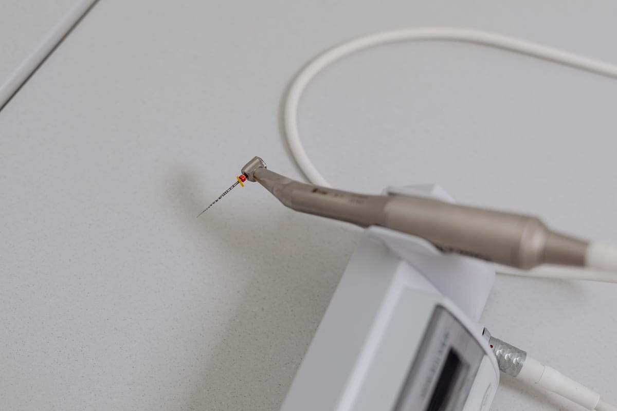 An endodontic file mounted in a dental handpiece, close up