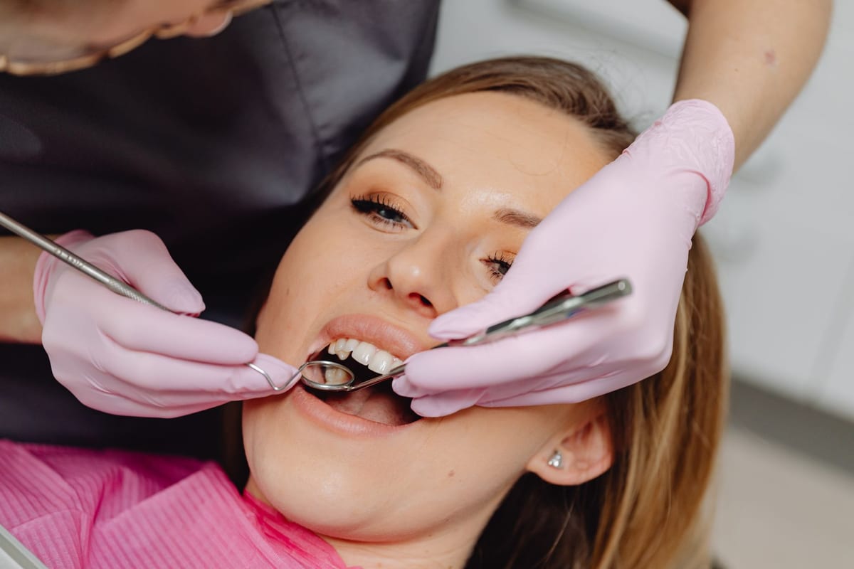 A patient in the chair during a dental examination with instruments in use